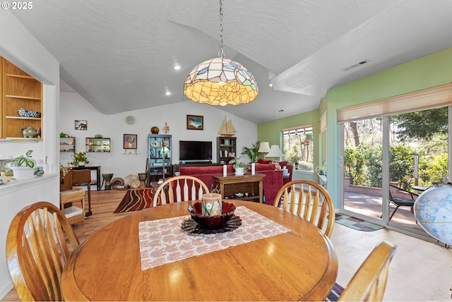 dining area with visible vents, vaulted ceiling, wood finished floors, and a textured ceiling