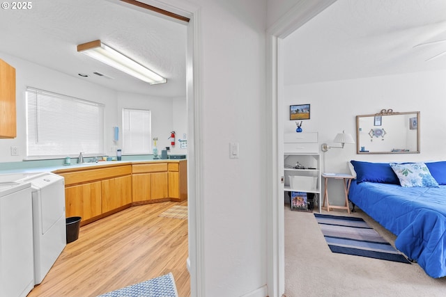 interior space with a sink, open floor plan, light countertops, light wood-style floors, and independent washer and dryer