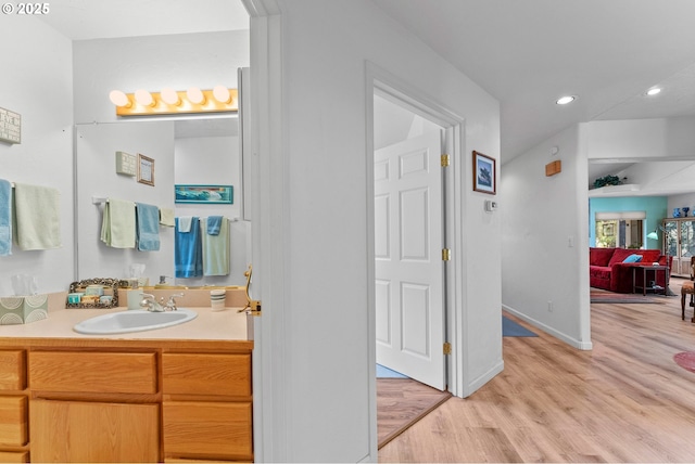 bathroom with wood finished floors, vanity, baseboards, and recessed lighting