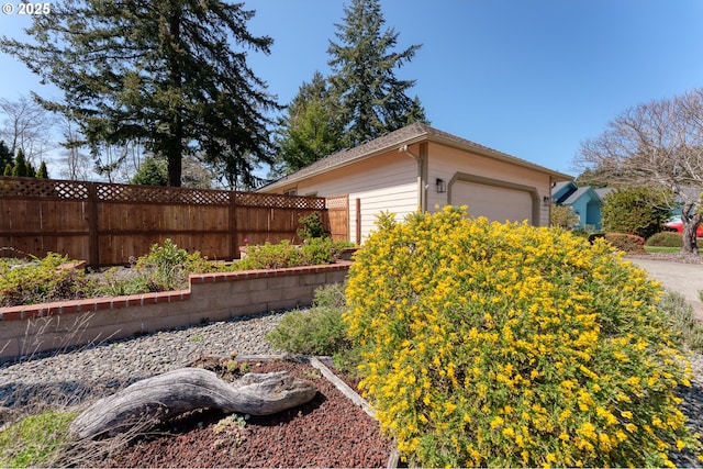 exterior space with an attached garage, an outbuilding, and fence