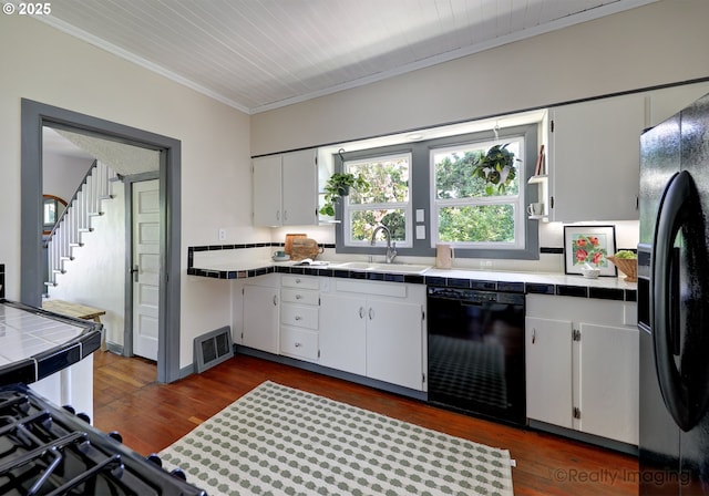 kitchen featuring black appliances, tile countertops, a sink, crown molding, and white cabinets