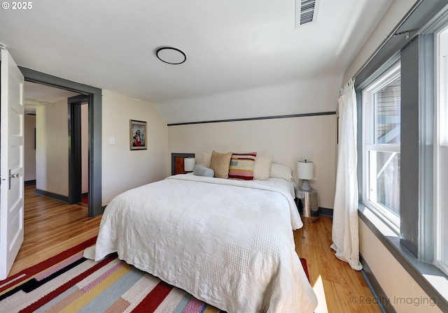 bedroom featuring light wood finished floors and vaulted ceiling