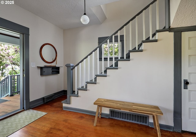 foyer entrance with hardwood / wood-style flooring, stairs, baseboards, and a textured ceiling