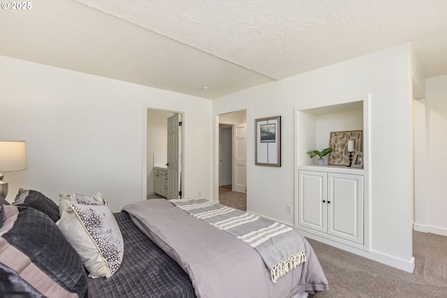 carpeted bedroom with a textured ceiling and ensuite bathroom