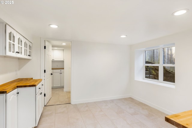 kitchen featuring wood counters, white cabinets, and light tile patterned flooring