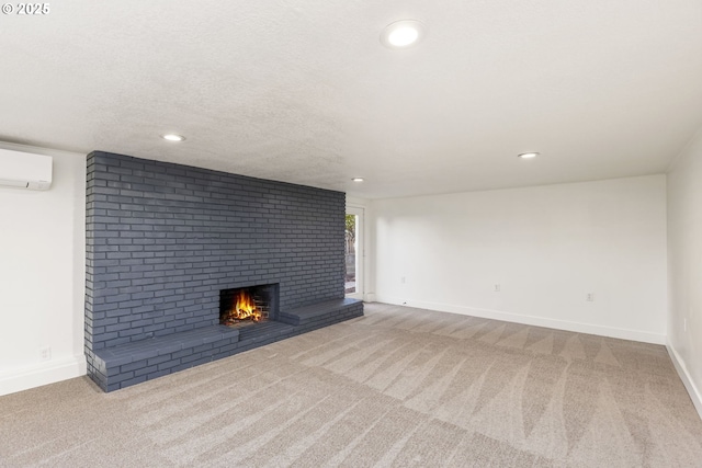 unfurnished living room featuring a brick fireplace, a wall mounted air conditioner, light colored carpet, and a textured ceiling