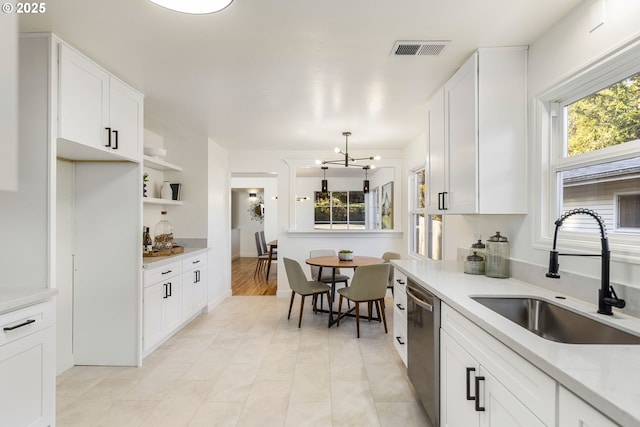 kitchen with white cabinetry, stainless steel dishwasher, sink, and hanging light fixtures