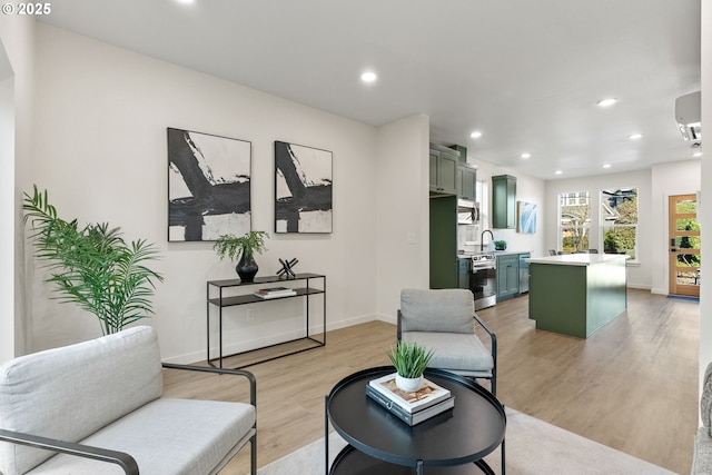 living room with sink, light hardwood / wood-style floors, and an AC wall unit