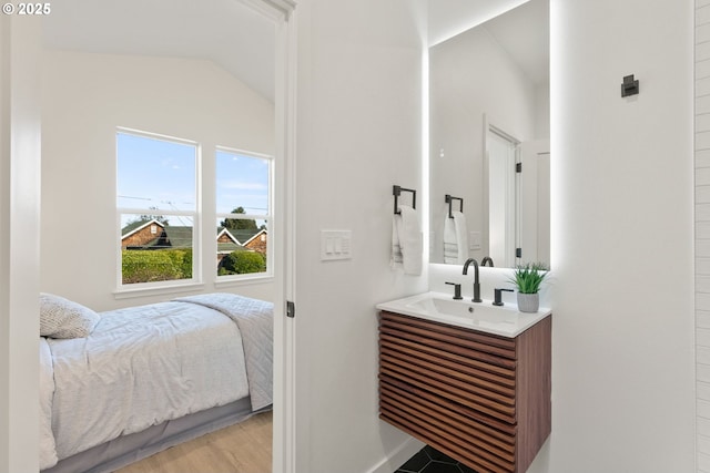 bedroom featuring vaulted ceiling, sink, and light wood-type flooring