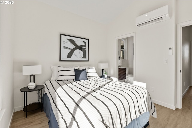 bedroom featuring vaulted ceiling, an AC wall unit, and light hardwood / wood-style floors