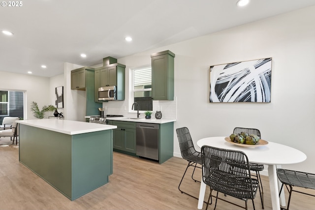 kitchen featuring tasteful backsplash, light hardwood / wood-style flooring, stainless steel appliances, and green cabinetry