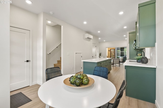 dining area featuring an AC wall unit, sink, and light hardwood / wood-style flooring