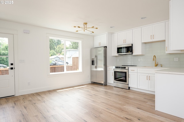 4103 SE Olsen St Unit 8, Milwaukie, OR 97222 - kitchen featuring stainless steel appliances, light wood-style floors, decorative backsplash, and light countertops