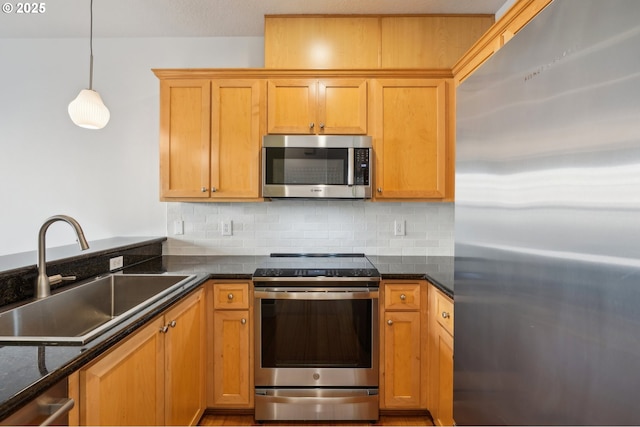 727 SE 33rd Pl Unit 21, Portland, OR 97214 - kitchen featuring stainless steel appliances, a sink, tasteful backsplash, decorative light fixtures, and dark stone counters