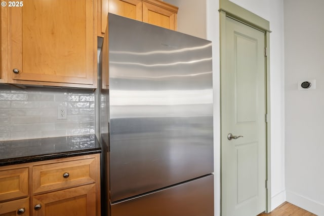 727 SE 33rd Pl Unit 21, Portland, OR 97214 - kitchen with freestanding refrigerator, tasteful backsplash, dark stone countertops, baseboards, and wood finished floors