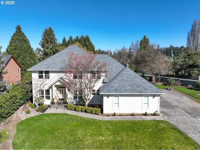 traditional-style house with a shingled roof and a front yard