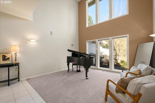 living area featuring carpet, a high ceiling, baseboards, and tile patterned flooring