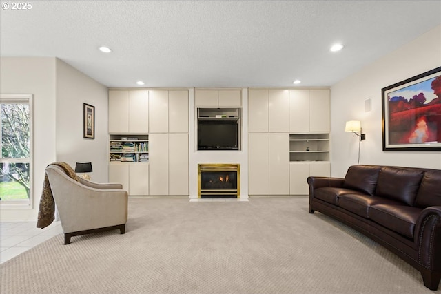 living room featuring a fireplace with flush hearth, recessed lighting, light colored carpet, and a textured ceiling