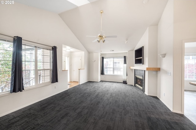 unfurnished living room featuring high vaulted ceiling, a tile fireplace, a ceiling fan, baseboards, and dark carpet