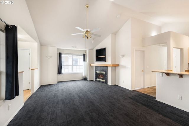 unfurnished living room with a ceiling fan, baseboards, dark carpet, and a tiled fireplace