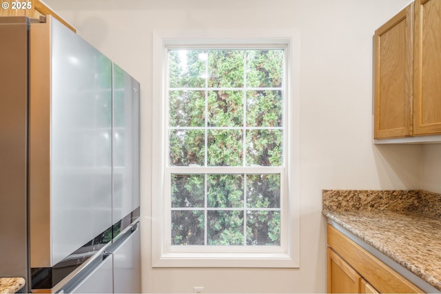 kitchen with light stone counters and freestanding refrigerator