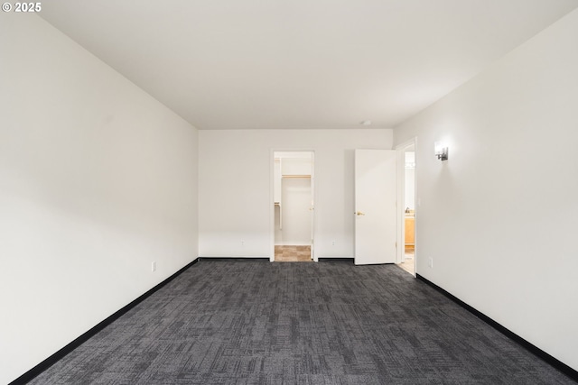 unfurnished room featuring dark colored carpet and baseboards