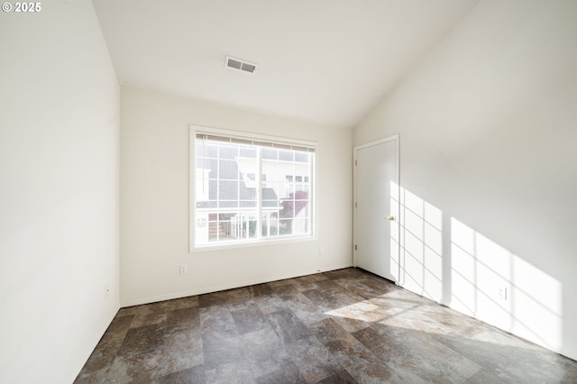 empty room featuring stone finish flooring, visible vents, and vaulted ceiling