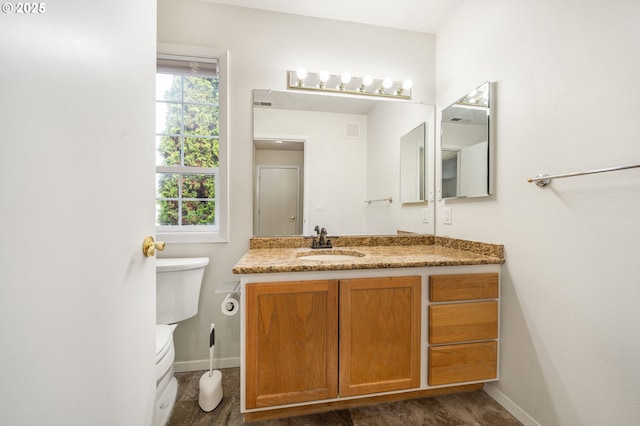 bathroom with toilet, baseboards, and vanity