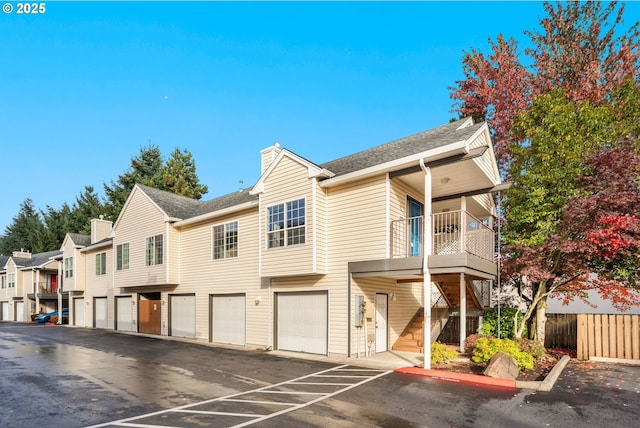 view of front facade featuring a residential view, a chimney, fence, and community garages