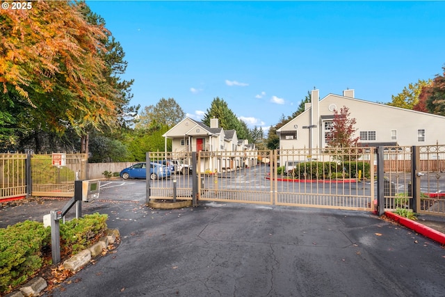 view of street featuring a gate, a gated entry, and curbs