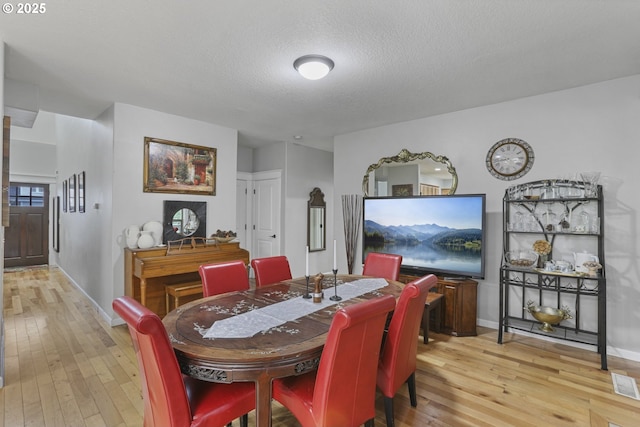 dining area featuring light hardwood / wood-style floors and a textured ceiling