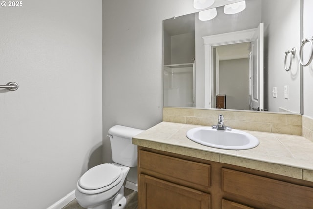 bathroom with vanity, baseboards, walk in shower, and toilet