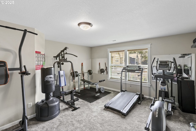 workout area featuring carpet floors, a textured ceiling, and baseboards