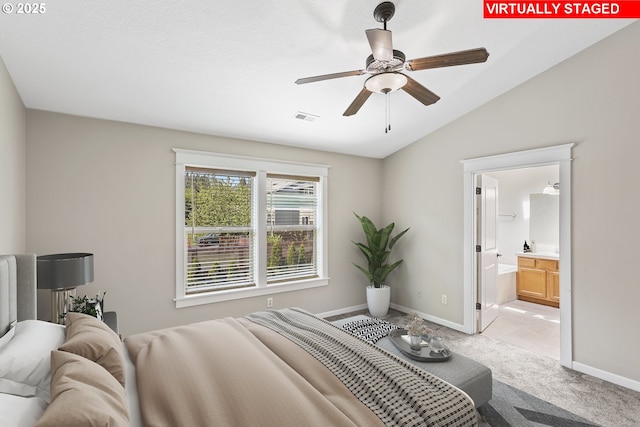 bedroom with visible vents, lofted ceiling, baseboards, ensuite bathroom, and light colored carpet