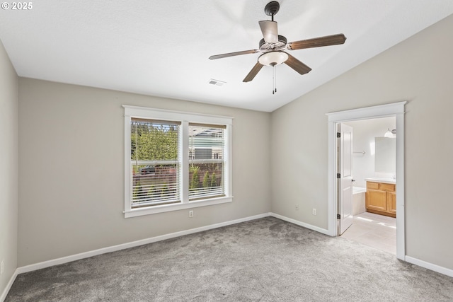 unfurnished bedroom with visible vents, lofted ceiling, light carpet, baseboards, and ensuite bathroom