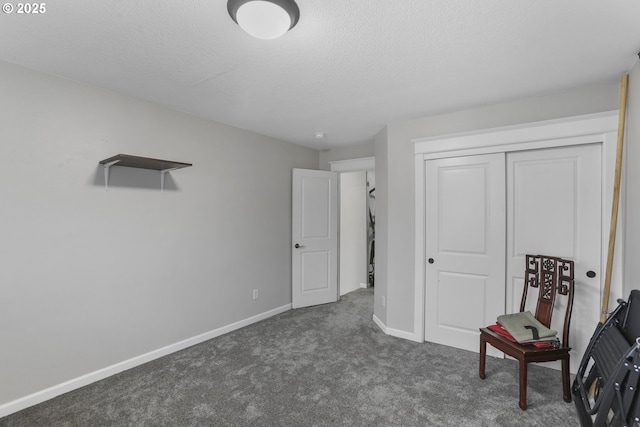 interior space featuring dark colored carpet, a textured ceiling, and a closet