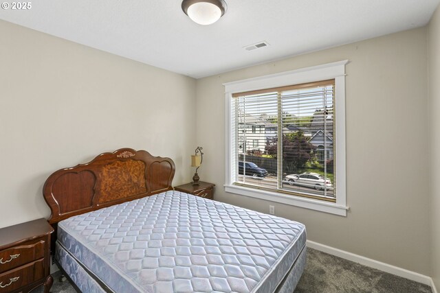 bedroom featuring baseboards, dark colored carpet, and visible vents