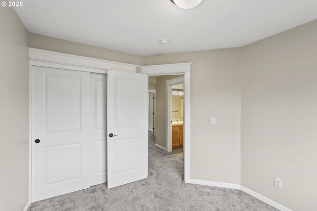 unfurnished bedroom with baseboards, a closet, and light carpet