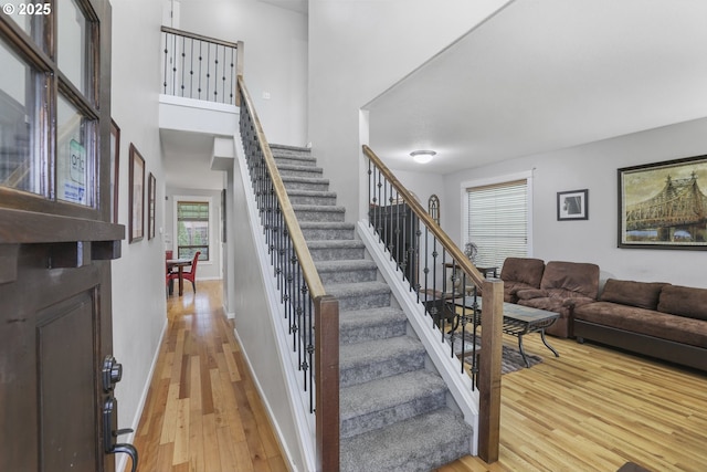 stairway featuring a towering ceiling and wood-type flooring