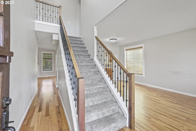 stairway with baseboards, a high ceiling, and wood finished floors