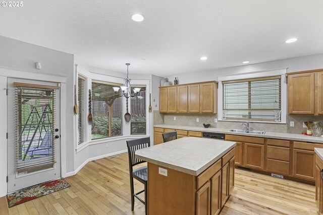 kitchen with tasteful backsplash, sink, an inviting chandelier, a center island, and hanging light fixtures