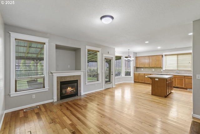 kitchen featuring baseboards, light countertops, a chandelier, and a center island
