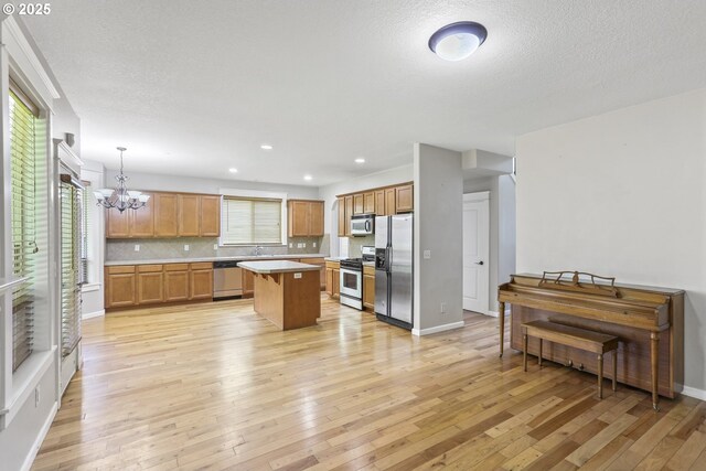 kitchen with an inviting chandelier, light countertops, light wood-style flooring, stainless steel appliances, and a kitchen island