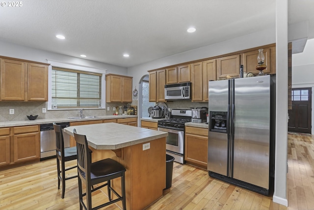 kitchen with sink, appliances with stainless steel finishes, tasteful backsplash, a kitchen island, and a breakfast bar area