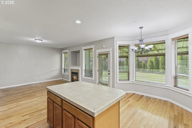 kitchen with a textured ceiling, a notable chandelier, baseboards, and light wood-style flooring