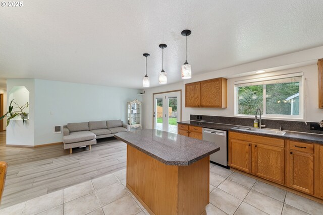 kitchen with stainless steel dishwasher, dark countertops, plenty of natural light, a center island, and a sink