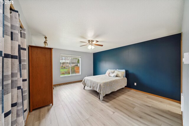 bedroom with a ceiling fan, baseboards, and light wood finished floors
