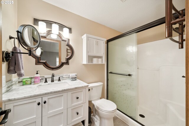 bathroom with vanity, a stall shower, and toilet
