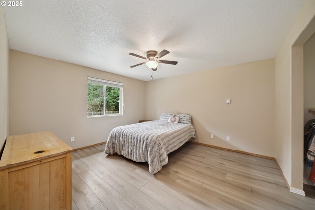 bedroom with a textured ceiling, baseboards, a ceiling fan, and light wood-style floors