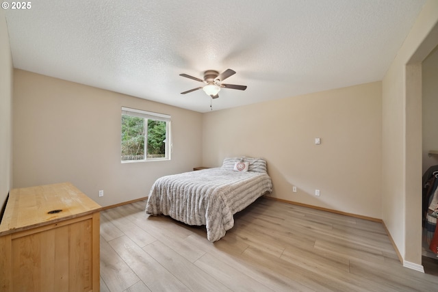 35363 Bayside Gardens Rd, Nehalem, OR 97131 - bedroom with light wood-style floors, baseboards, a textured ceiling, and ceiling fan